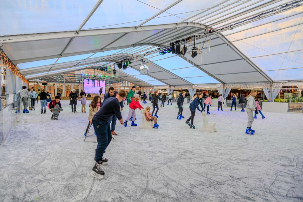 Schaatsers en kinderen met pinguïns op de overdekte baan